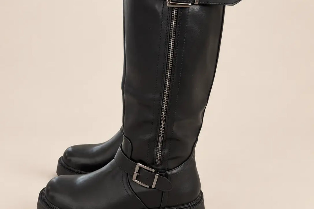Kleid und Rock mit Strumpfhose: schwarze kniehohe Stiefel mit Schnallen und Reißverschluss vor hellem Studiohintergrund | Lisa’s Boutique