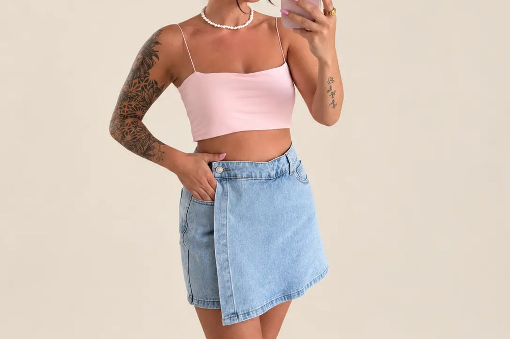 Frau in hellblauem Jeans Hosenrock mit rosa Top und schwarzen Boots | Lisa’s Boutique