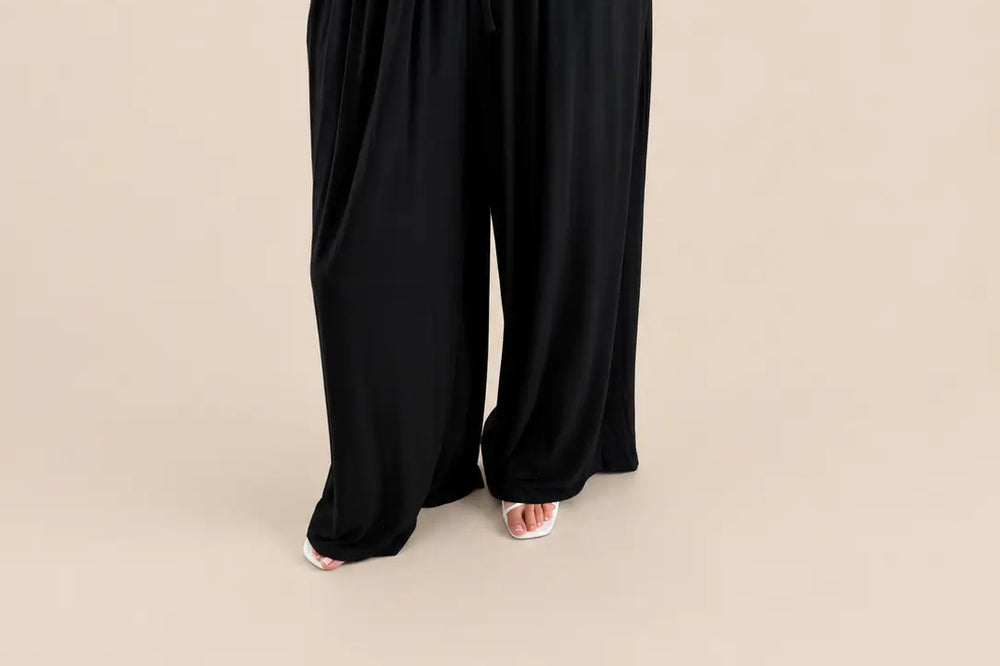 Outfit Konzert Damen: weite schwarze Hose mit Bindeband am Bund und Oberteil mit Leoprint vor hellem Studiohintergrund | Lisa’s Boutique