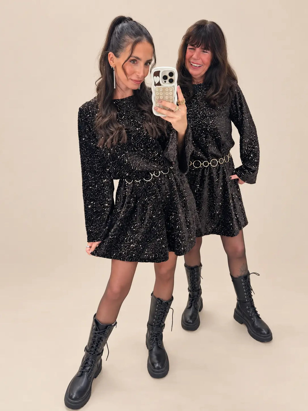 Weihnachtsoutfit Damen: zwei Frauen in schwarzen Paillettenkleidern mit Gürtel, schwarzer Strumpfhose und Schnürboots | Lisa’s Boutique