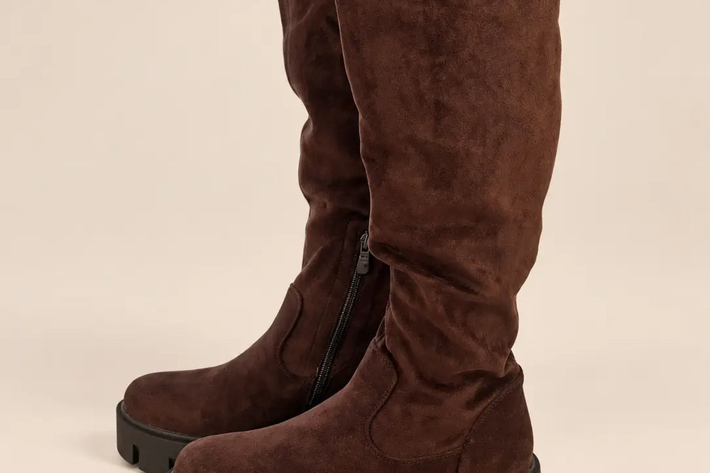 Kleid mit Stiefeln kombinieren: kniehohe braune Stiefel mit grober Sohle vor hellem Studiohintergrund | Lisa’s Boutique