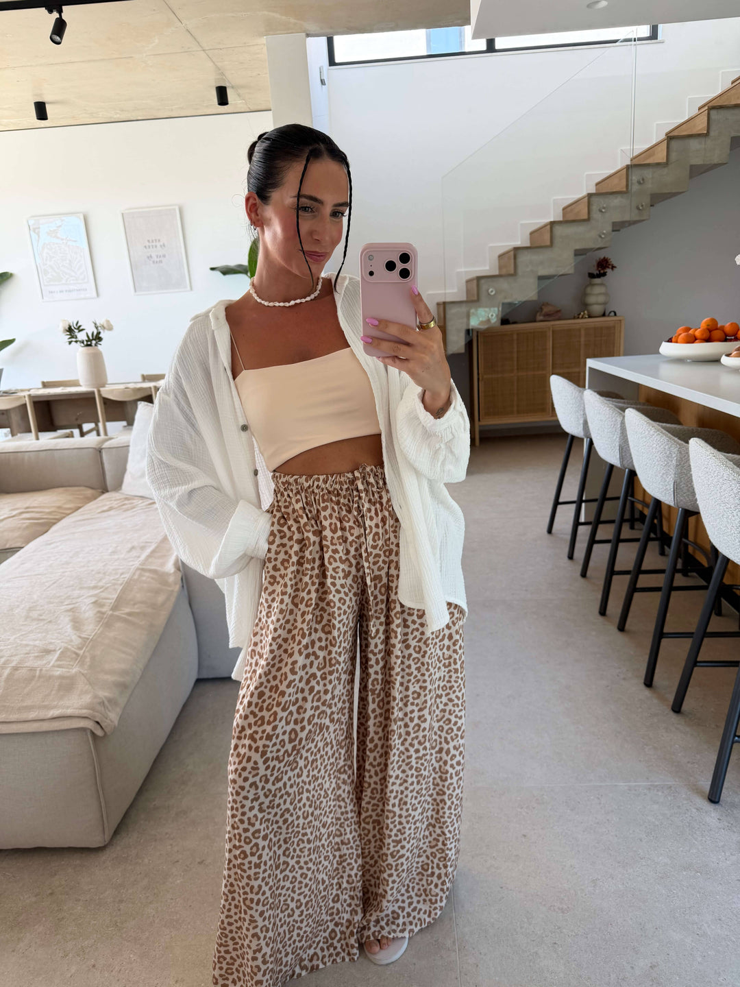 Frau in weiter Leoprint Hose in Beige mit hellem Trägertop und offener weißer Musselinbluse | Lisa's Boutique