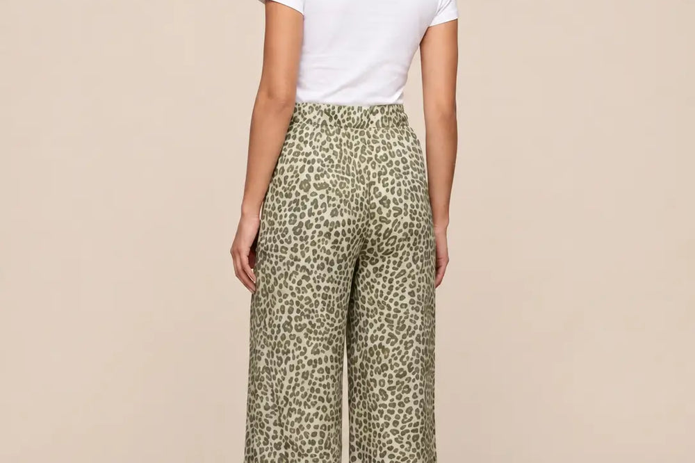 Khaki kombinieren: weite Hose mit Leoprint in Khaki-Tönen zu weißem Shirt, Rückansicht vor hellem Studiohintergrund | Lisa’s Boutique