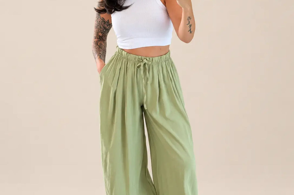 Welche Farbe passt zu Salbeigrün: lockere Hose in Salbei mit weißem Top und weißen Sandalen vor hellem Studiohintergrund | Lisa’s Boutique