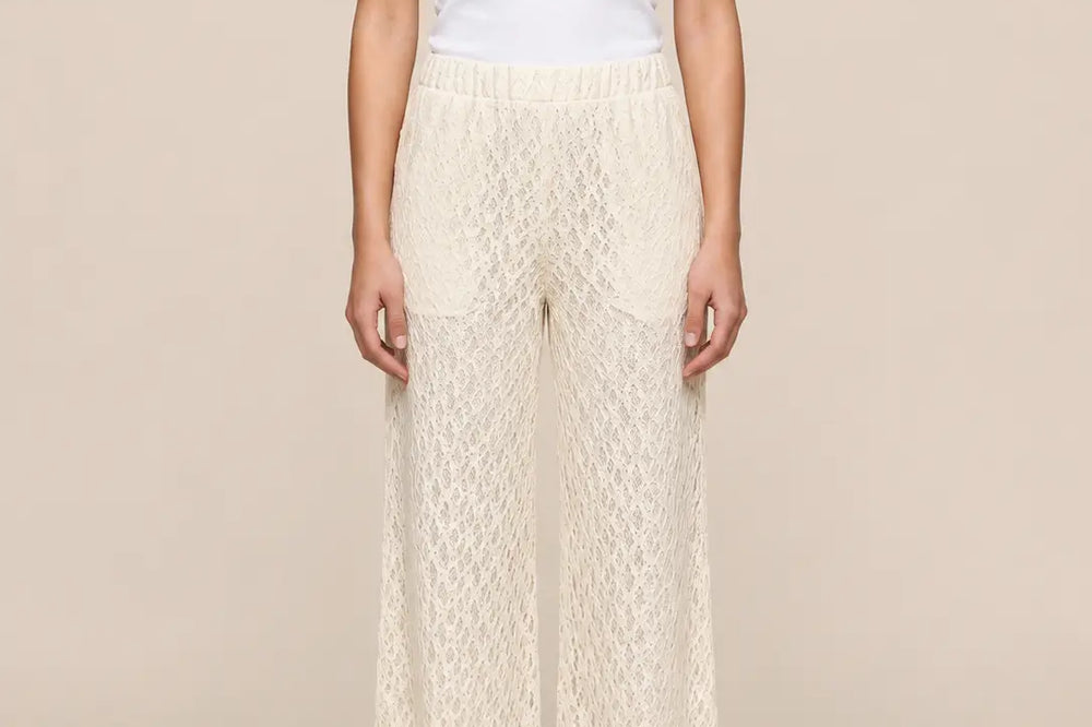 Weiße Hose kombinieren: cremefarbene Spitzenhose mit weißem Top vor beigem Studiohintergrund | Lisa’s Boutique