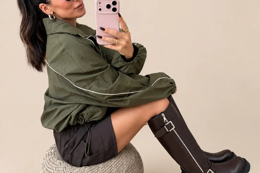Festival Outfit Damen: khakifarbene Windbreaker-Jacke, Shorts und braune Stiefel vor hellem Studiohintergrund | Lisa’s Boutique