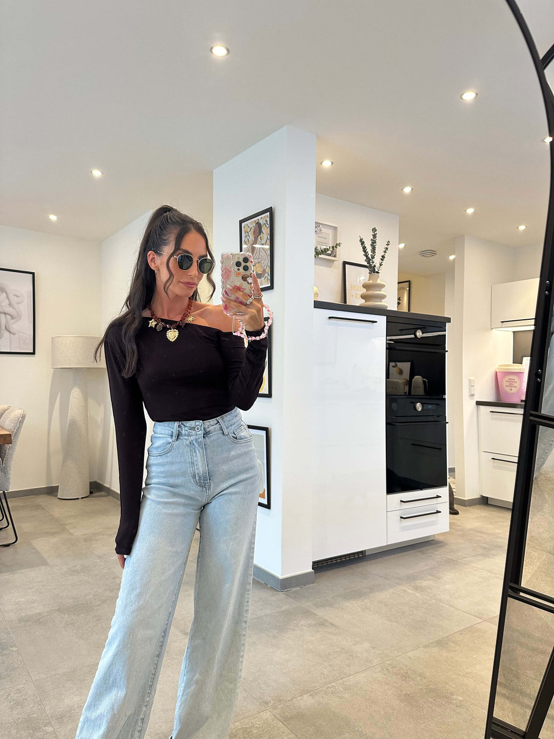 Model trägt ein enganliegendes, dunkelbraunes Langarmshirt mit Rundhalsausschnitt, kombiniert mit einer hellblauen High-Waist-Jeans – minimalistischer Look mit klarer Silhouette.