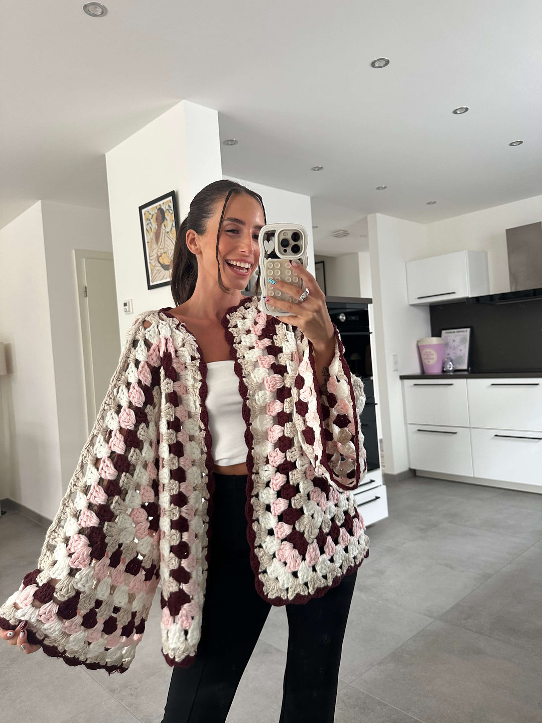 Modell trägt gehäkelten Cardigan mit weiten Ärmeln und Blumenmuster – lisasboutique.de