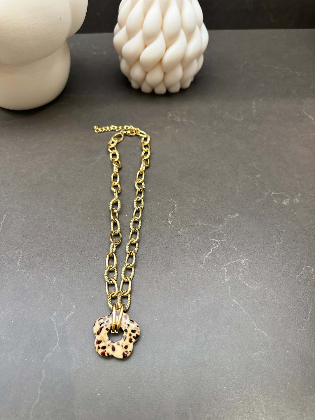 Goldene Gliederkette mit Leo-Anhänger in Blütenform auf dunklem Untergrund
