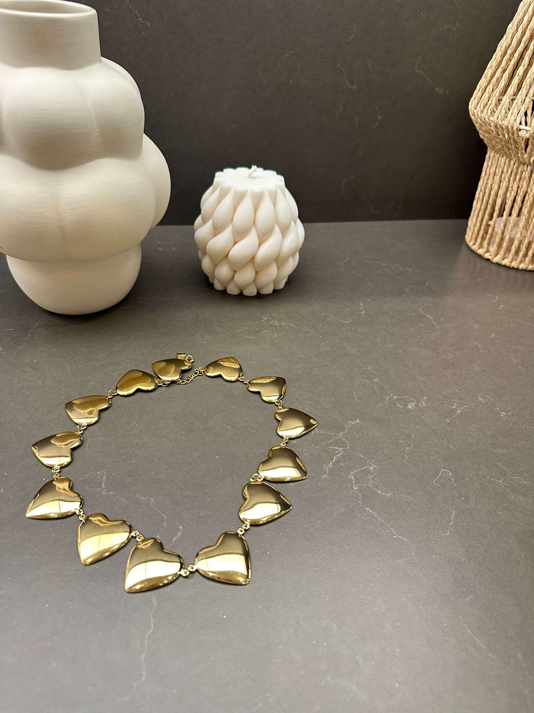Goldene Kette mit vielen Herz-Anhängern in Reihe auf schwarzem Untergrund
