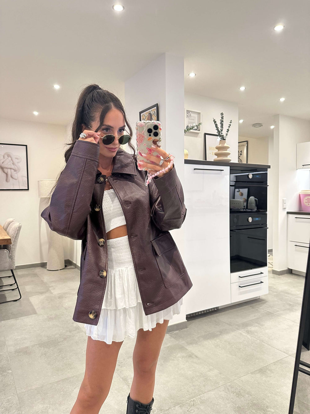Model trägt eine bordeauxrote oversized Kunstlederjacke mit Knöpfen und Taschen