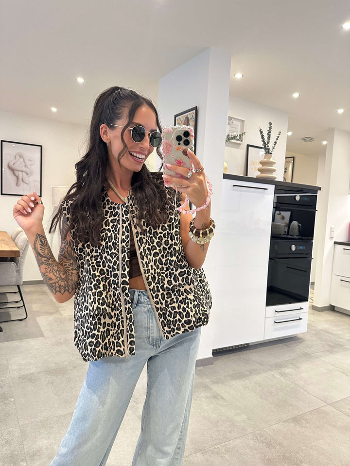Frau trägt eine flauschige Leopardenweste in Beige-Braun mit lockerer Passform über einem Top und einer hellblauen Jeans.