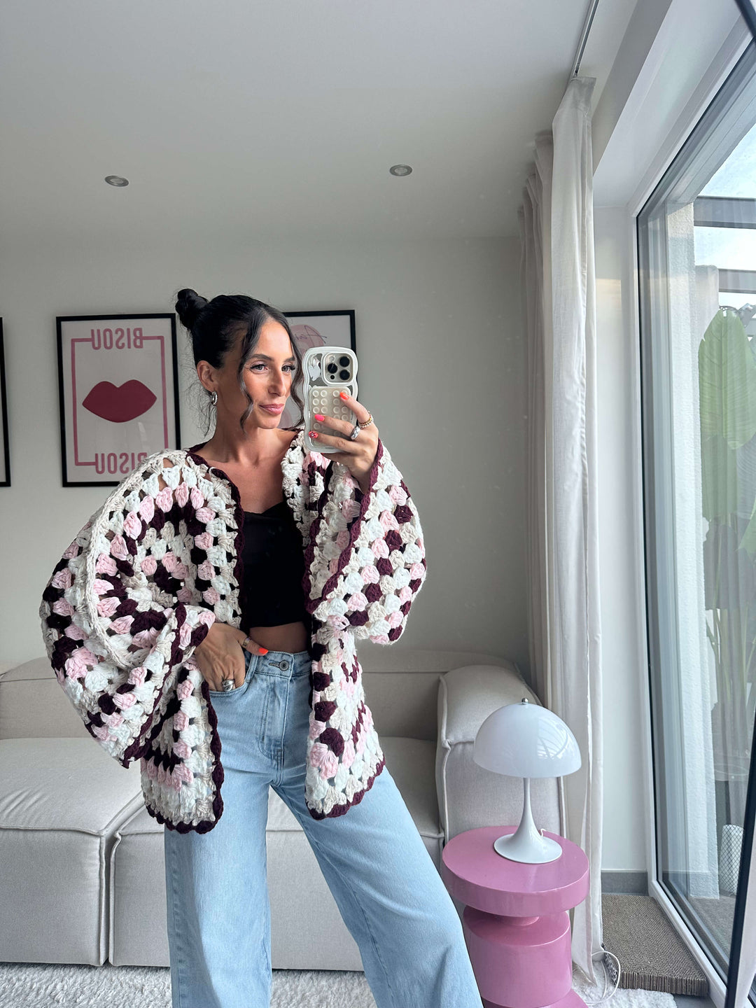 Lisa trägt einen gehäkelten Cardigan in Creme und Braun mit großem Blumenmuster, kombiniert mit schwarzem Top und hellblauer Jeans – Lisas Boutique