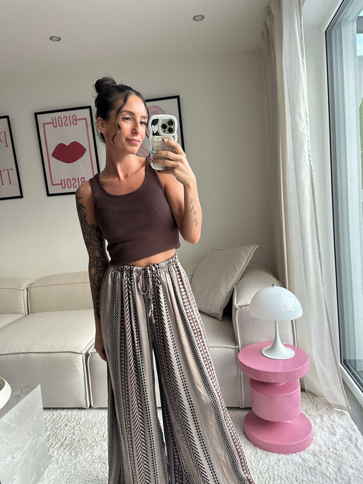 Lisa trägt ein braunes Stricktop und eine weite Hose mit Muster – Lisas-Boutique.