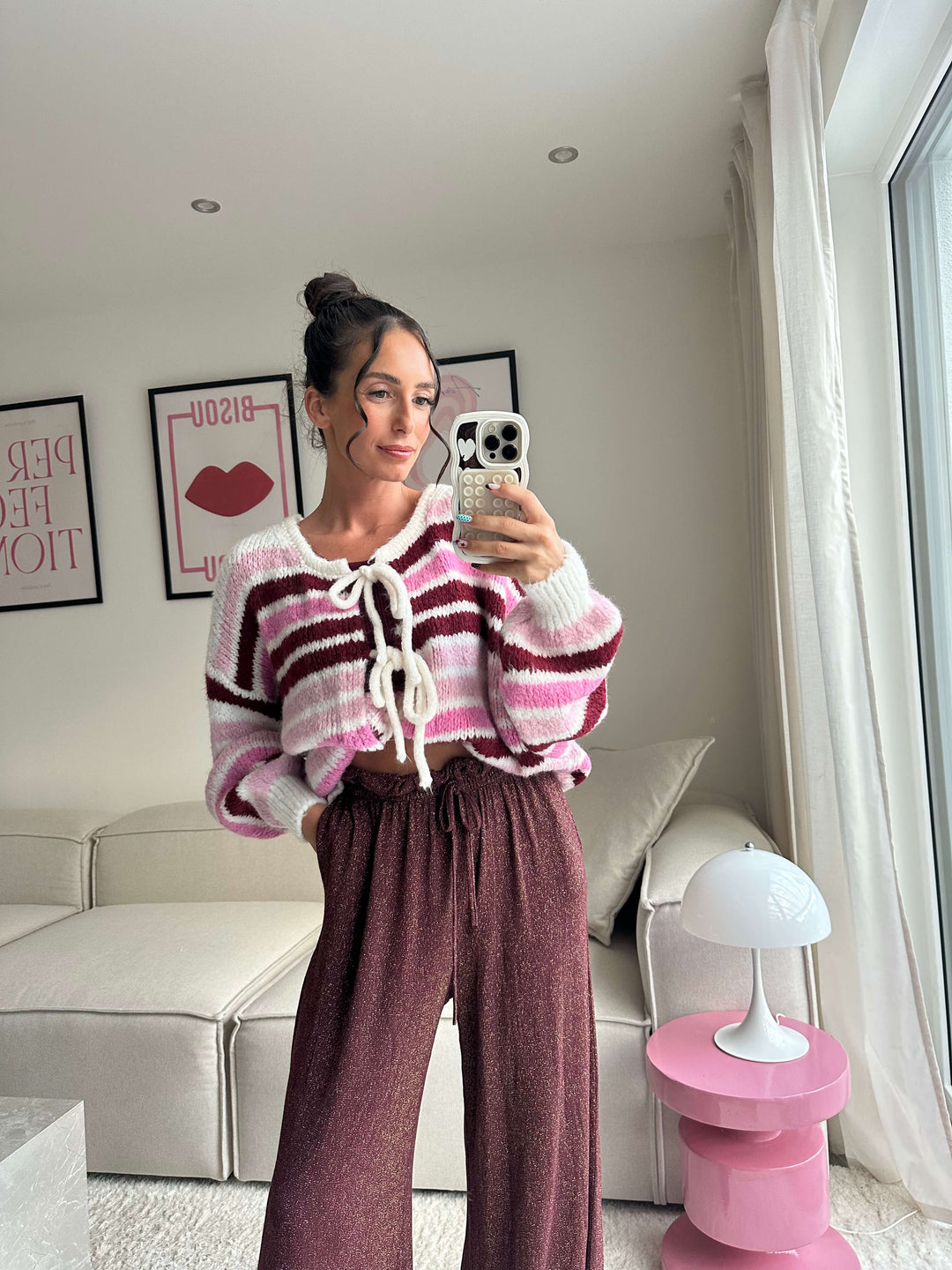 Lisa trägt einen pink-gestreiften Strickpullover mit Schnürung und eine weite Glitzerhose – Lisas-Boutique.