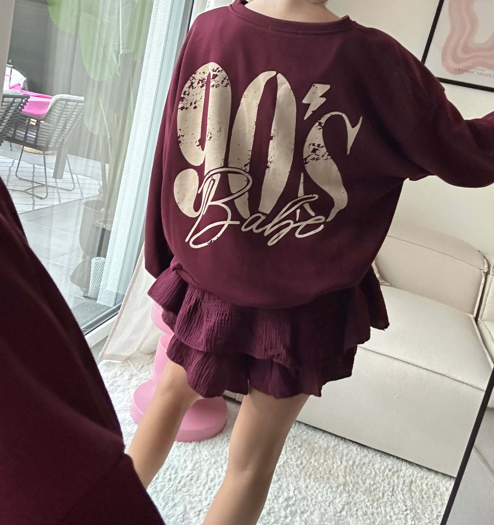 Lisa trägt einen bordeauxfarbenen Oversize-Pullover mit 90er-Print und einen passenden Rock – Lisas-Boutique.