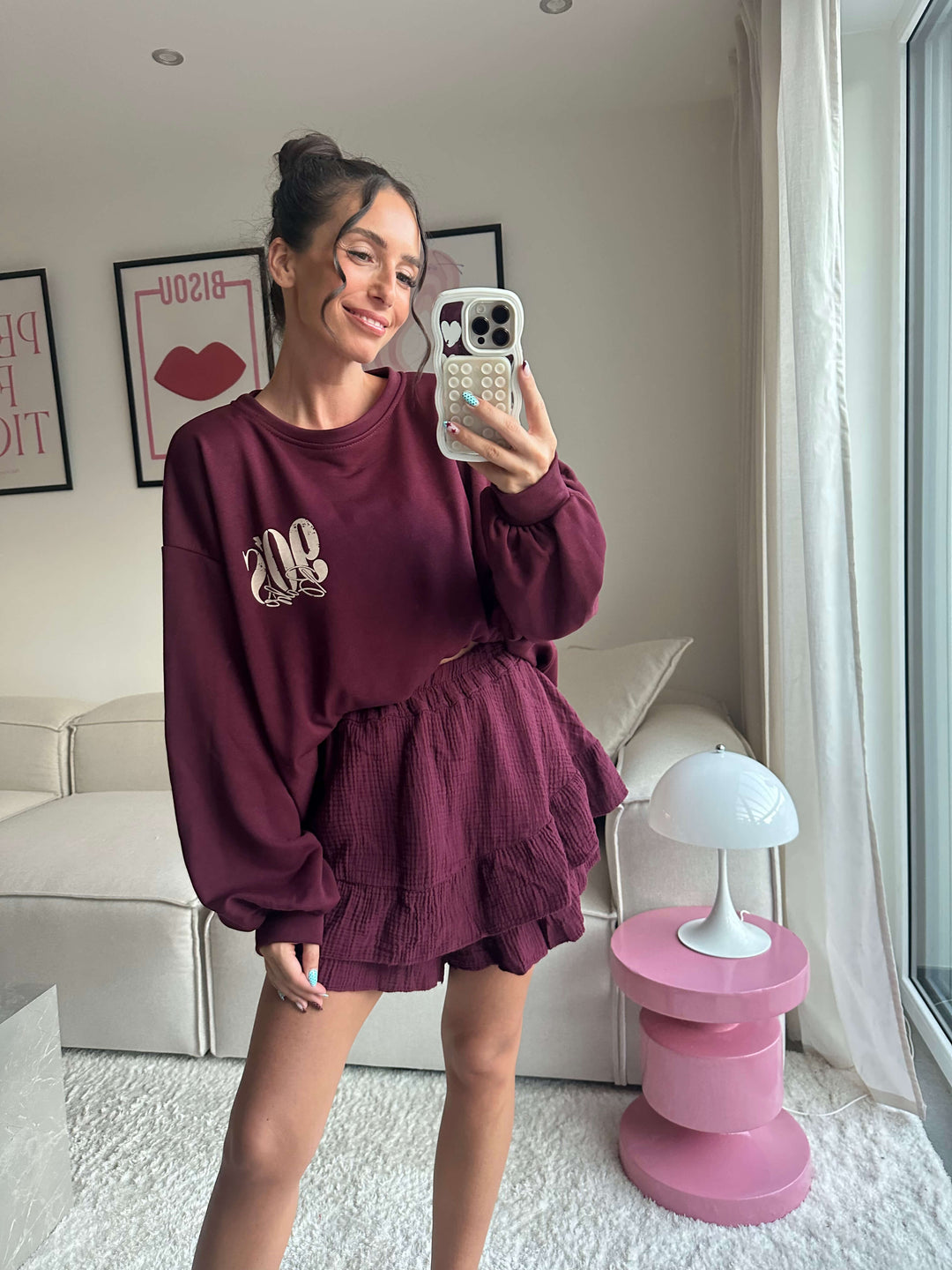 Lisa trägt einen bordeauxfarbenen Oversize-Pullover mit 90er-Schriftzug und einen passenden Rock – Lisas-Boutique.