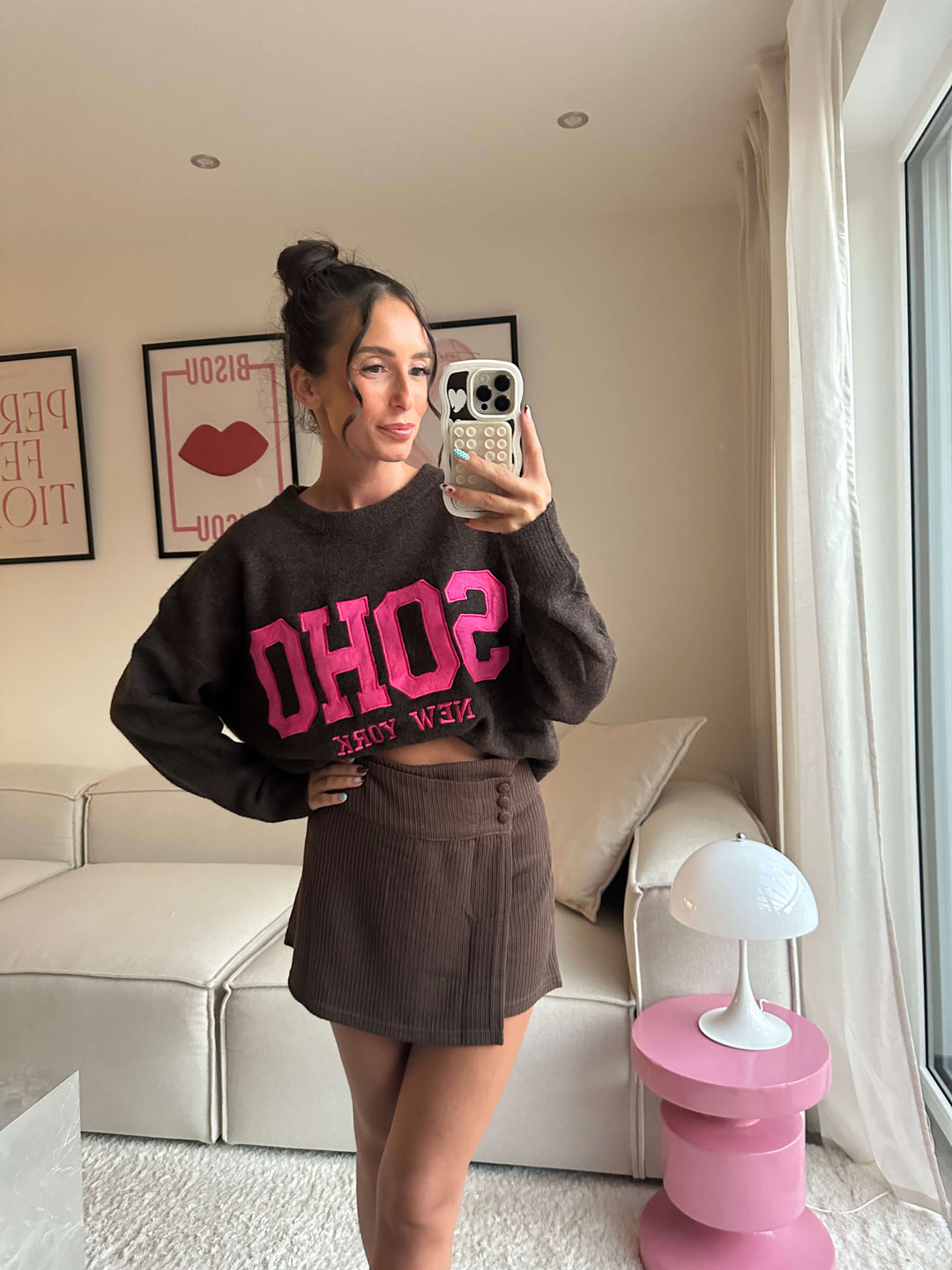 Lisa trägt einen dunkelbraunen „SOHO New York“-Sweater mit pinkem Schriftzug und einen braunen Minirock – Lisas-Boutique.
