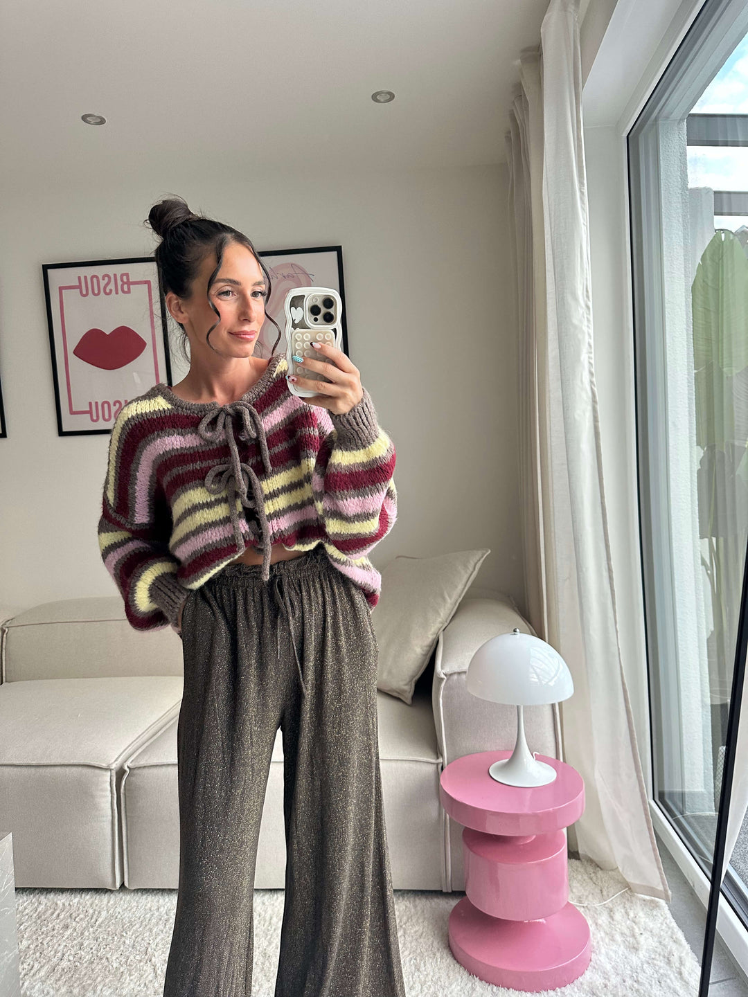 Lisa trägt einen gestreiften Strickpullover mit Schnürung und eine glitzernde, weite Hose – Lisas-Boutique