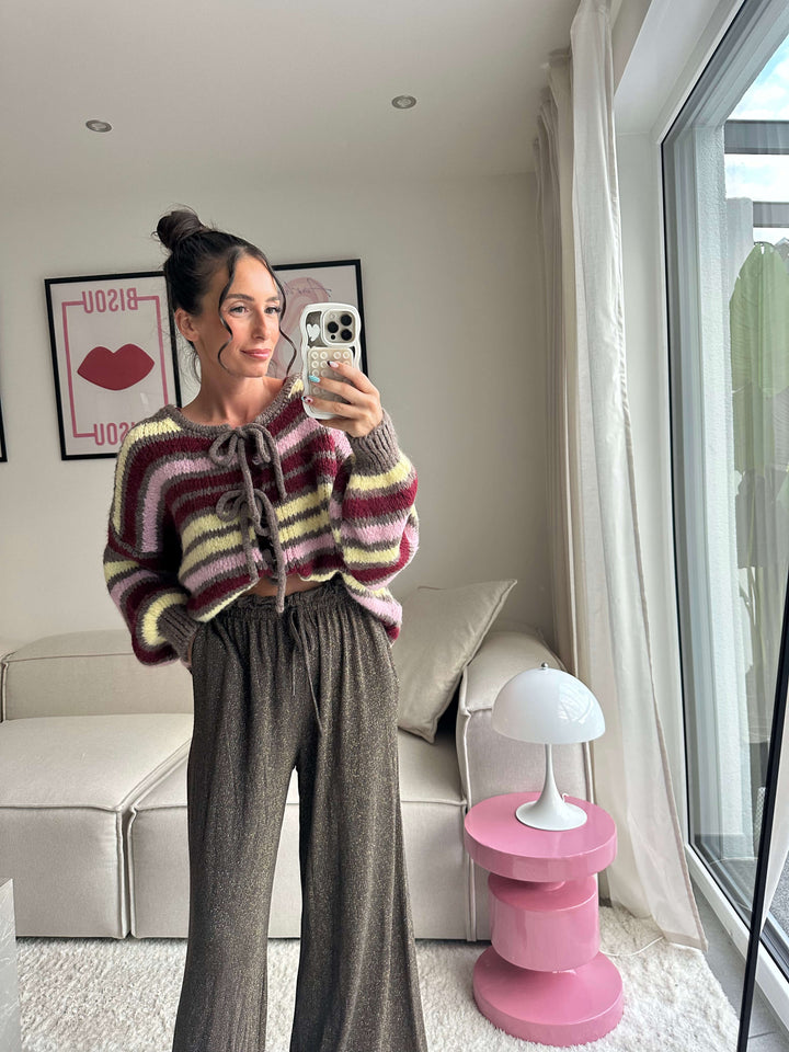 Lisa trägt einen gestreiften Strickpullover mit Schnürung und eine glitzernde, weite Hose – Lisas-Boutique