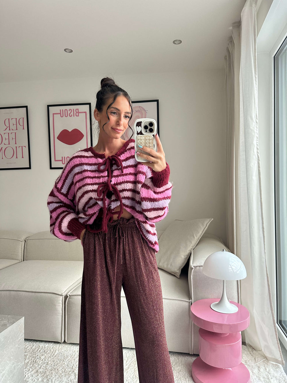 Lisa trägt einen pink-gestreiften Strickpullover mit Schnürung und eine glitzernde, weite Hose – Lisas-Boutique.