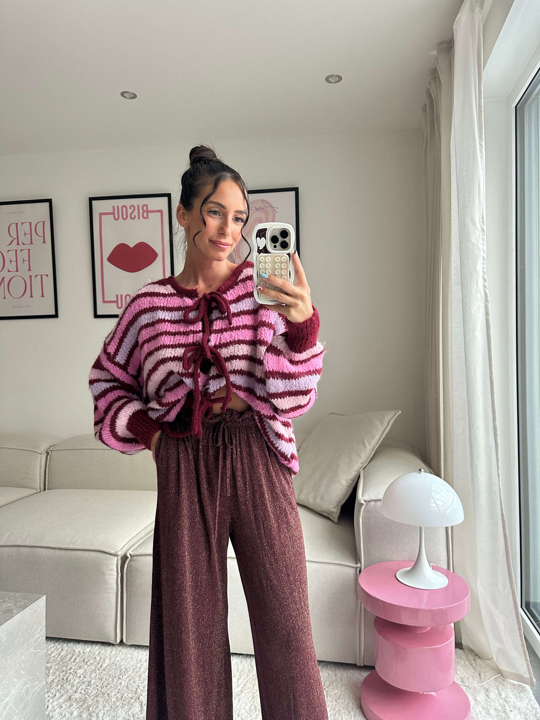 Lisa trägt einen pink-gestreiften Strickpullover mit Schnürung und eine glitzernde, weite Hose – Lisas-Boutique.