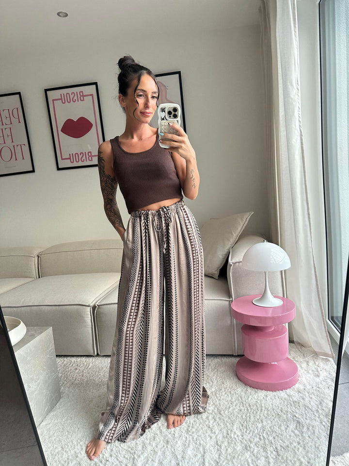 Lisa trägt ein braunes Stricktop und eine weite Hose mit Ethno-Muster – Lisas-Boutique.