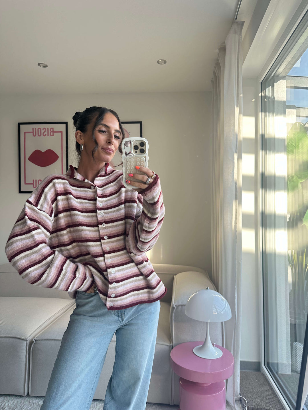 Lisa trägt einen gestreiften Strickcardigan in Bordeaux und Creme mit Knopfleiste, kombiniert mit hellblauer Jeans – Lisas Boutique