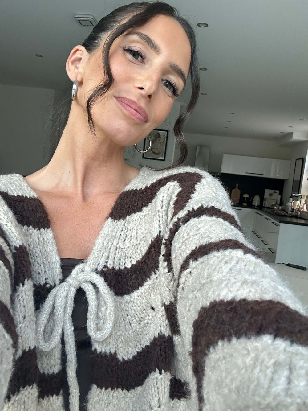 Lisa trägt einen gemütlichen Strickcardigan in Braun-Creme-Streifen mit Schleifenverschluss vorne – Lisas Boutique