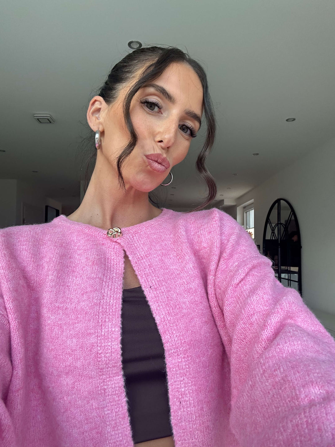 Lisa trägt einen weichen Strickcardigan in Rosa mit Hakenverschluss, kombiniert mit einem schwarzen Top – Lisas Boutique