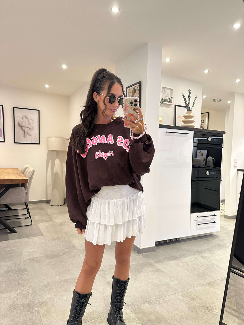 Brauner Cropped-Sweater mit weiß-pinker "Los Angeles"-Aufschrift, kombiniert mit weißem Mini-Rock.