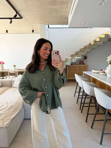 Blouse chemise kaki pour femme à col chemise, photo miroir dans le salon avec pantalon blanc | Lisa’s Boutique