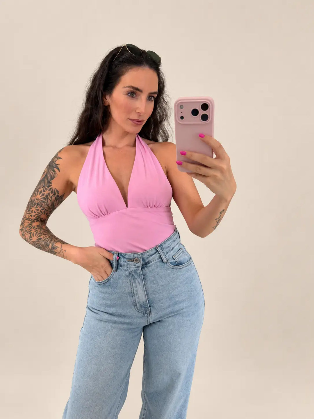 Pinkes Neckholder-Top für Damen mit tiefem V-Ausschnitt, Frontansicht am Model mit Jeans vor beigem Studiohintergrund