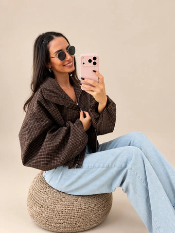 Brązowa kurtka damska oversize w kratę z zamkiem, na siedząco na pufie | Lisa’s Boutique