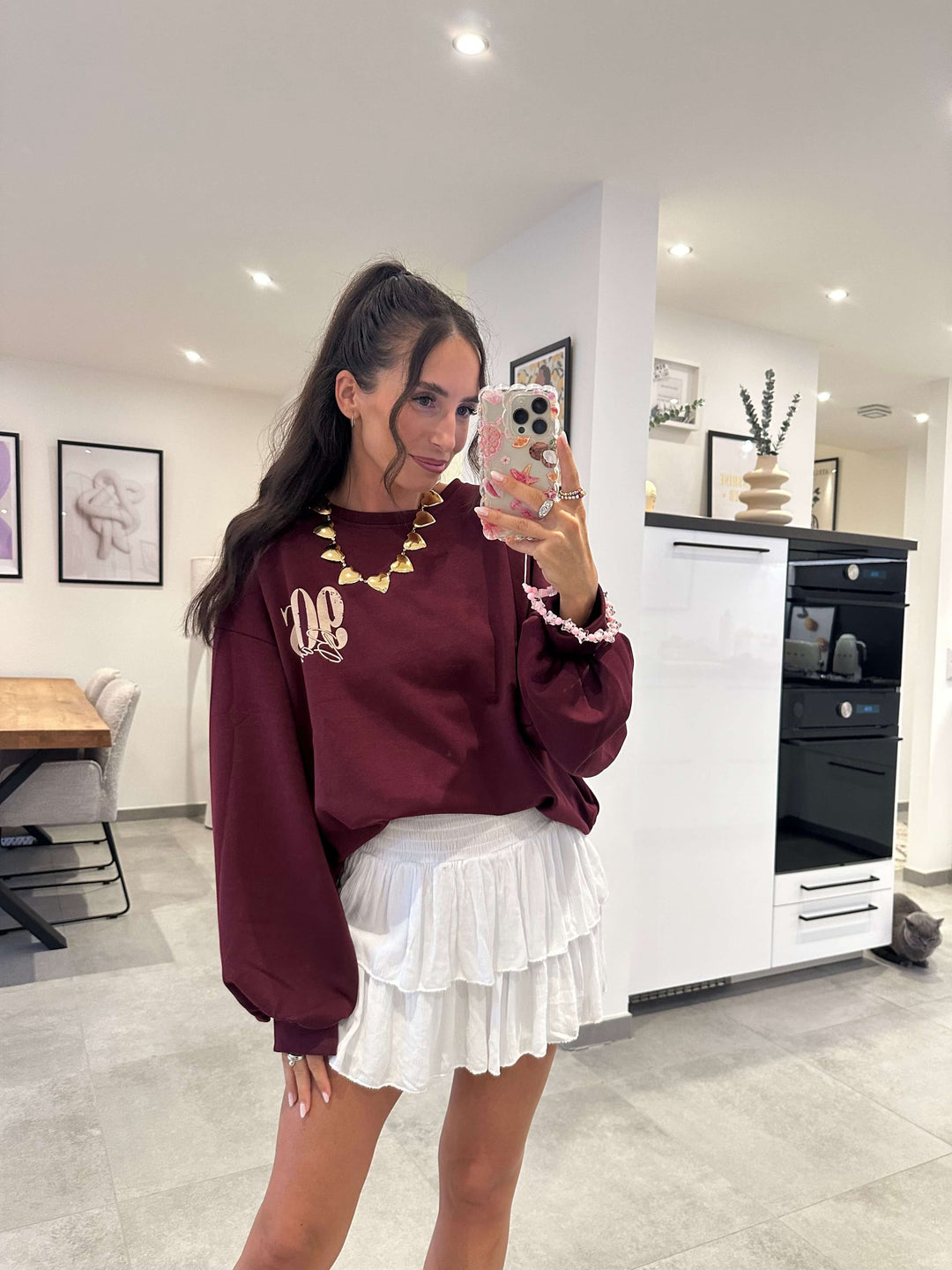  Bordeauxfarbener Pullover mit 90s Aufdruck, kombiniert mit weißem Rüschrock