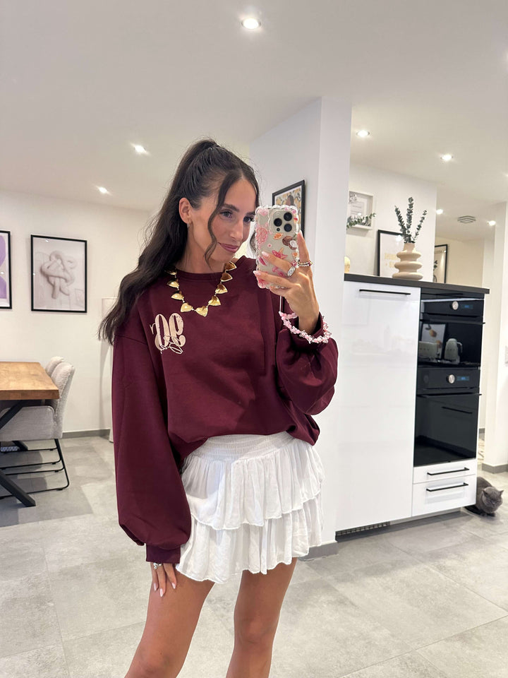  Bordeauxfarbener Pullover mit 90s Aufdruck, kombiniert mit weißem Rüschrock
