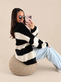 Strickjacke Damen in Schwarz/Weiß mit breiten Querstreifen, sitzend auf einem Sitzpouf zu Jeans | Lisa’s Boutique