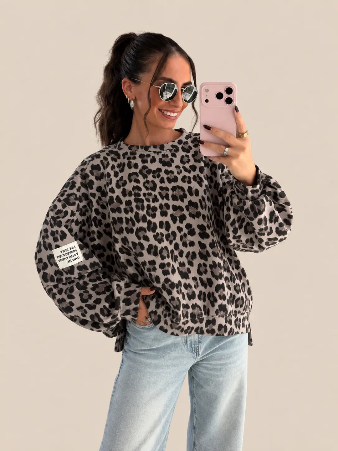 Sweat femme gris à motif léopard et écusson sur la manche, avec un jean clair | Lisa’s Boutique